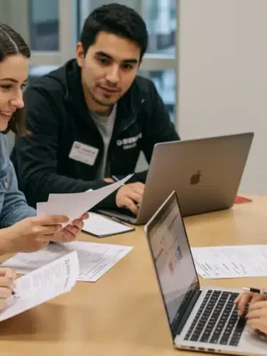 College students reviewing FAFSA forms and financial aid documents on laptops in a modern setting.