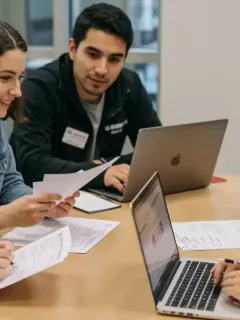 College students reviewing FAFSA forms and financial aid documents on laptops in a modern setting.